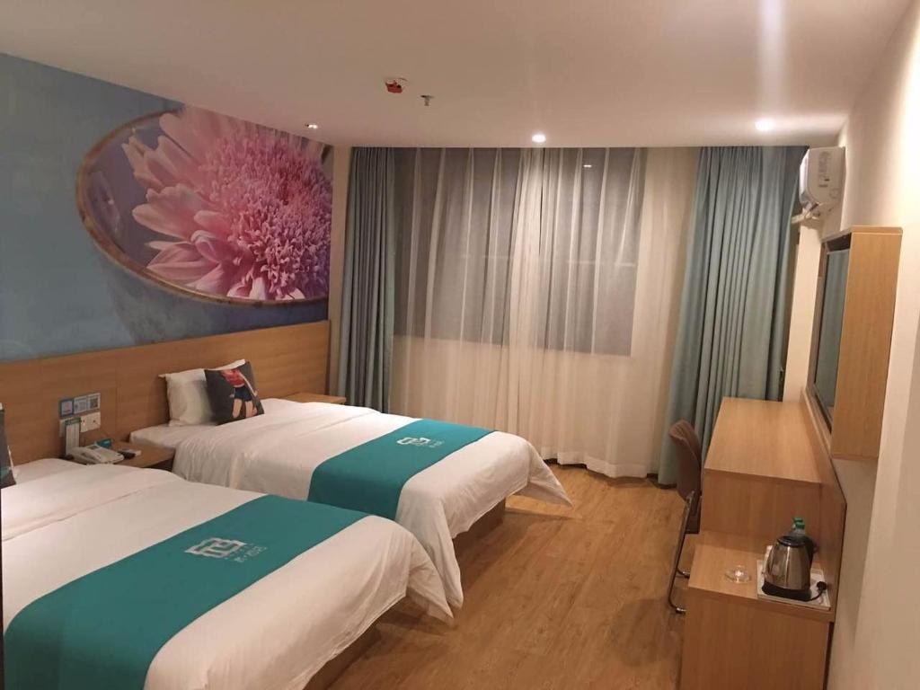 a hotel room with two beds and a painting on the wall at Pai Hotel Chongqing Wanzhou Gaosuntang Commerce And Trade City in Wanxian