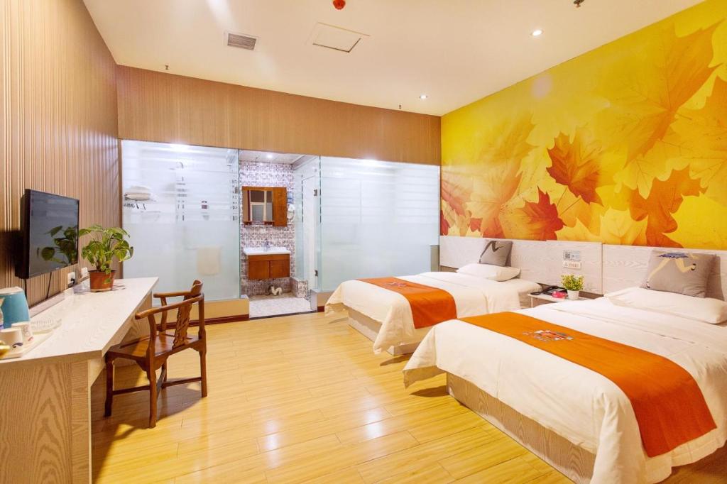 a hotel room with two beds and a desk and a television at Pai Hotel Zhuhai Career Technical College Seaview in Baigaonongchang