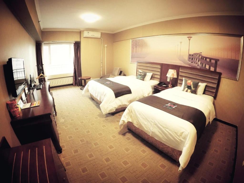 a hotel room with two beds and a window at Pai Hotel Harbin Saint Sophia Cathedral Yimian Street in Harbin