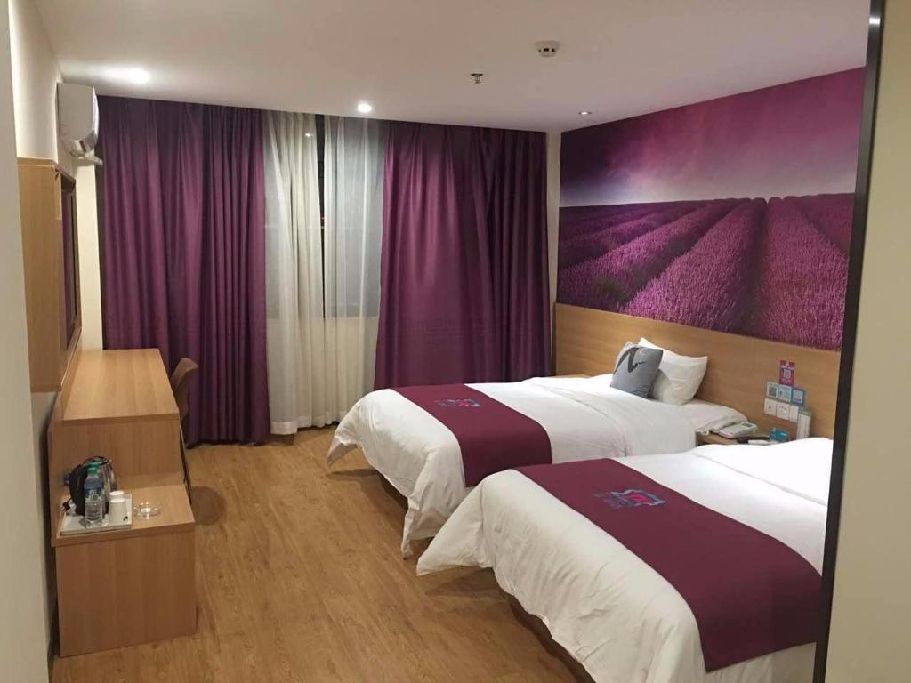 pokój hotelowy z 2 łóżkami i fioletowymi zasłonami w obiekcie Pai Hotel Jinan Railway Staion North Plaza Dikou Road w mieście Jinan