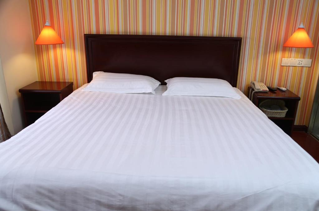 um quarto com uma grande cama branca com duas mesas de cabeceira em Pai Hotel Shenyang Railway Station em Shenyang