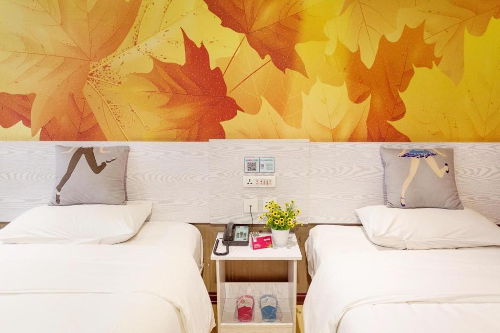 two beds in a room with leaves on the wall at Pai Hotel Nanjing West Shengtai Road Subway Station in Jiangning