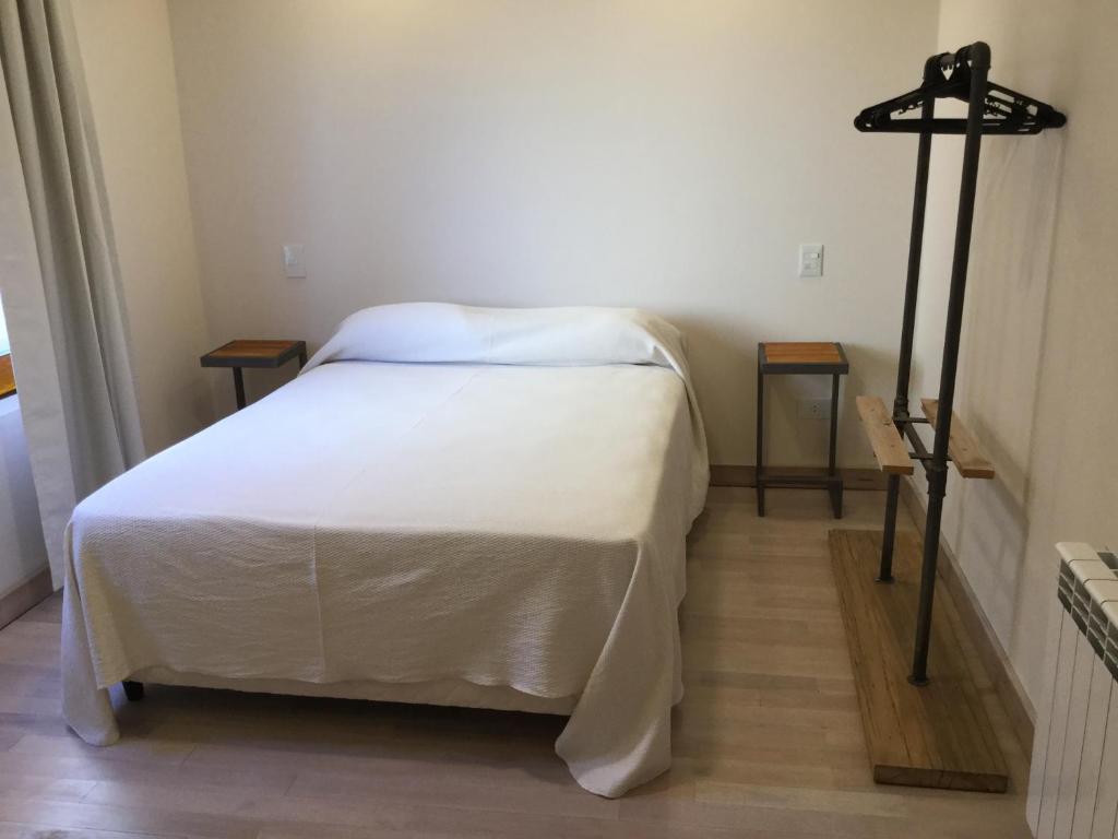een wit bed in een kamer met 2 tafels bij Wind Puerto Madryn in Puerto Madryn