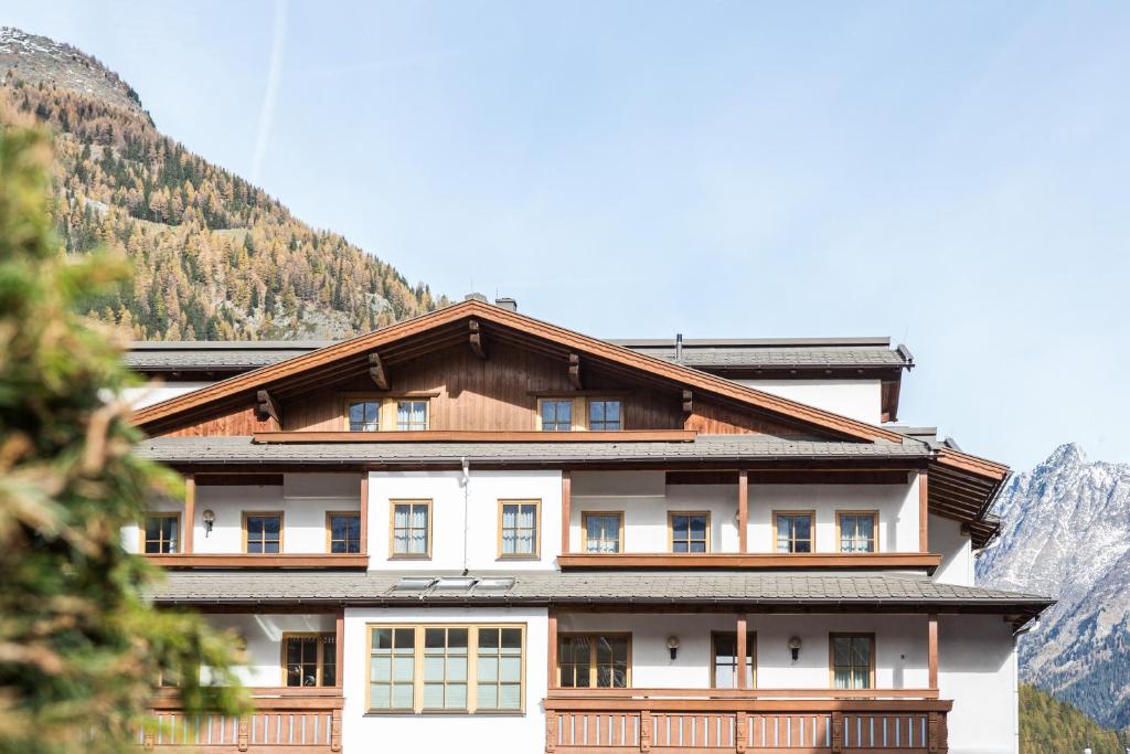 a house in the mountains with mountains in the background at Hotel Das Zentrum in Sölden