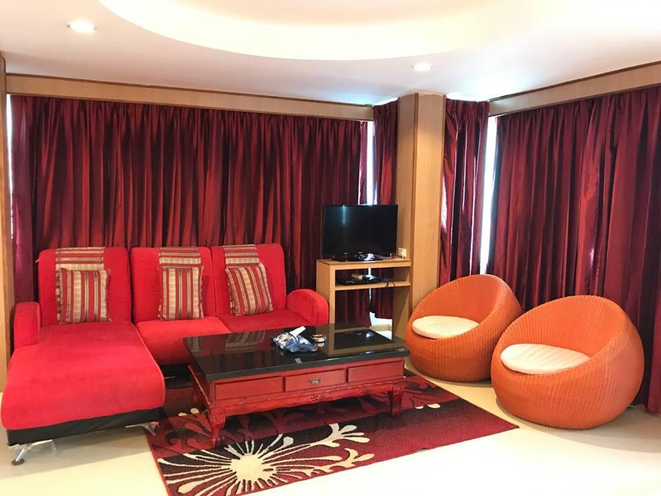 a living room with a red couch and two chairs at Star Residency Hotel in Pattaya