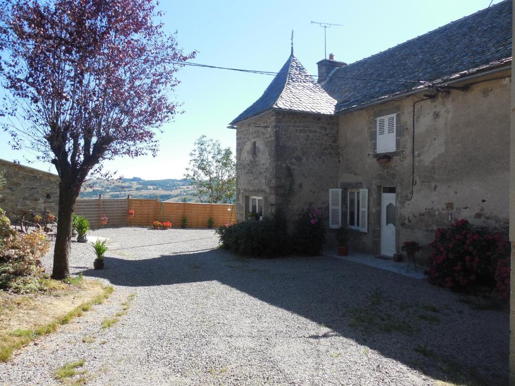 Saint-Félix-de-Lunel的住宿－Gite de Carboniès，一座古老的石头房子,前面有一棵树