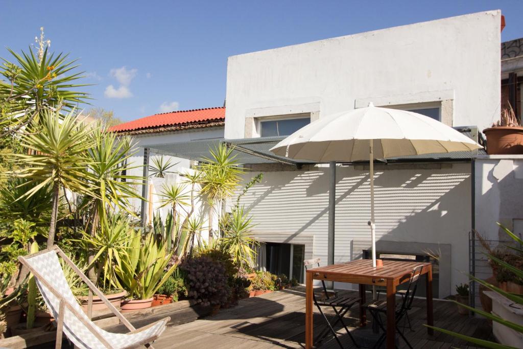 einen Tisch, Stühle und einen Regenschirm auf einer Terrasse in der Unterkunft Our Home In Lisbon - Apartments in Lissabon