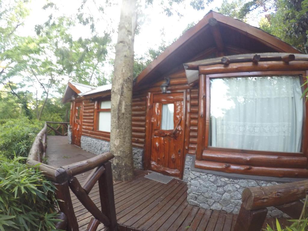 a cabin with a wooden deck and a tree at Cabañas Manamar in Villa Gesell
