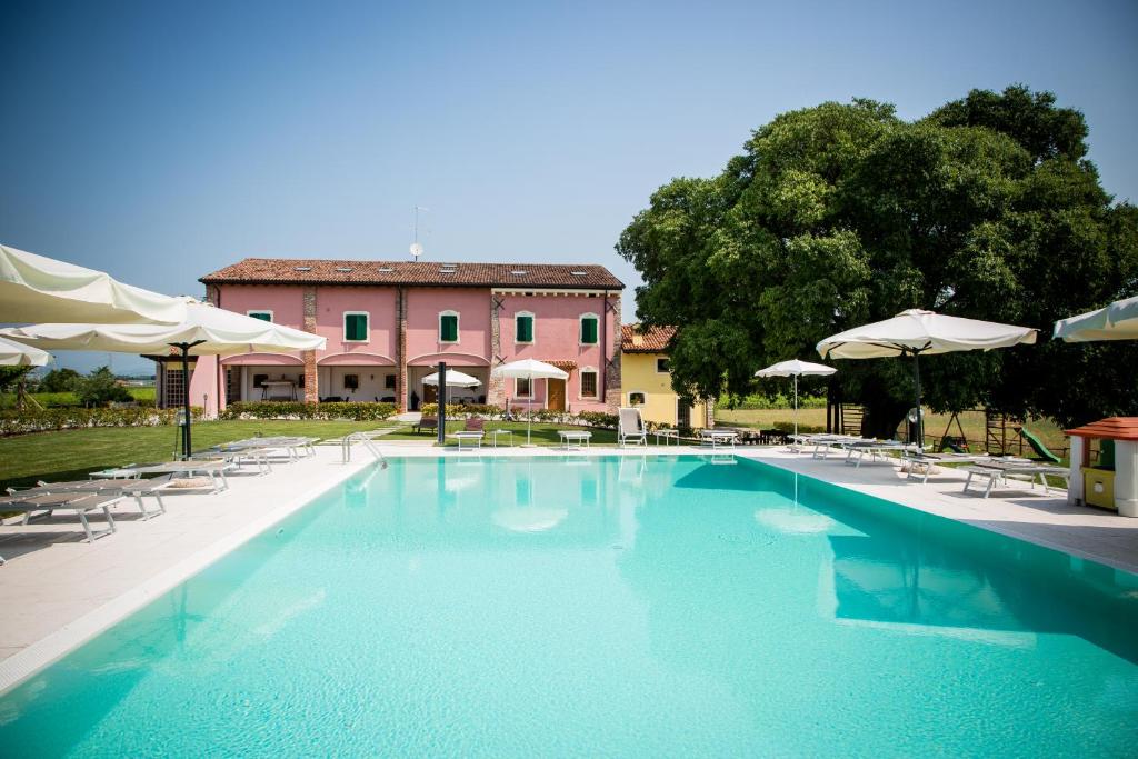 una piscina con sedie e ombrelloni di fronte a un edificio di Agriturismo Bosco Del Gal a Castelnuovo del Garda