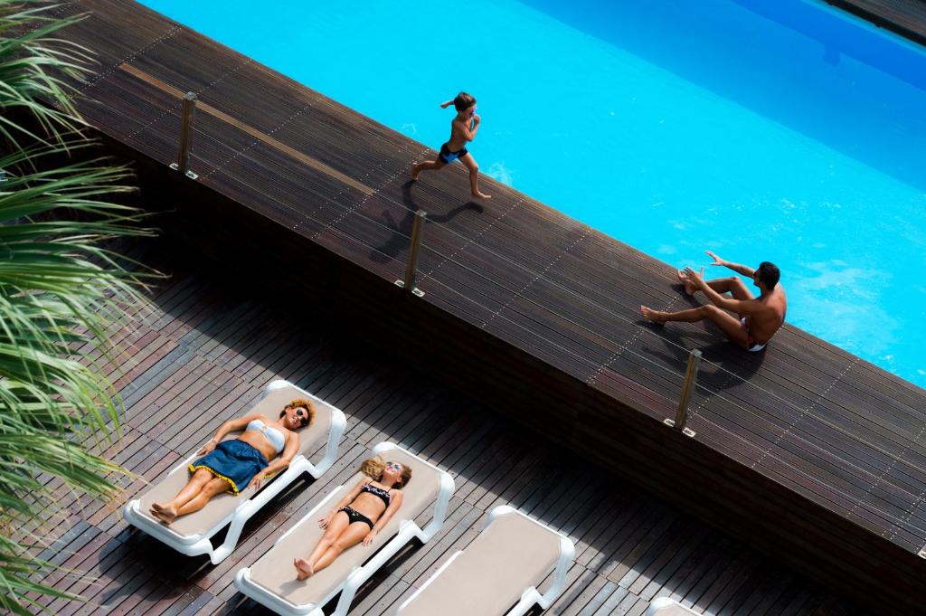 un grupo de personas sentadas en tumbonas junto a una piscina en Hotel Lido Europa, en Riccione