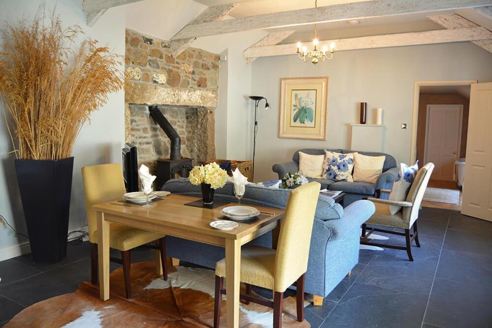 a living room with a table and a blue couch at Spring Water Barn in Helston