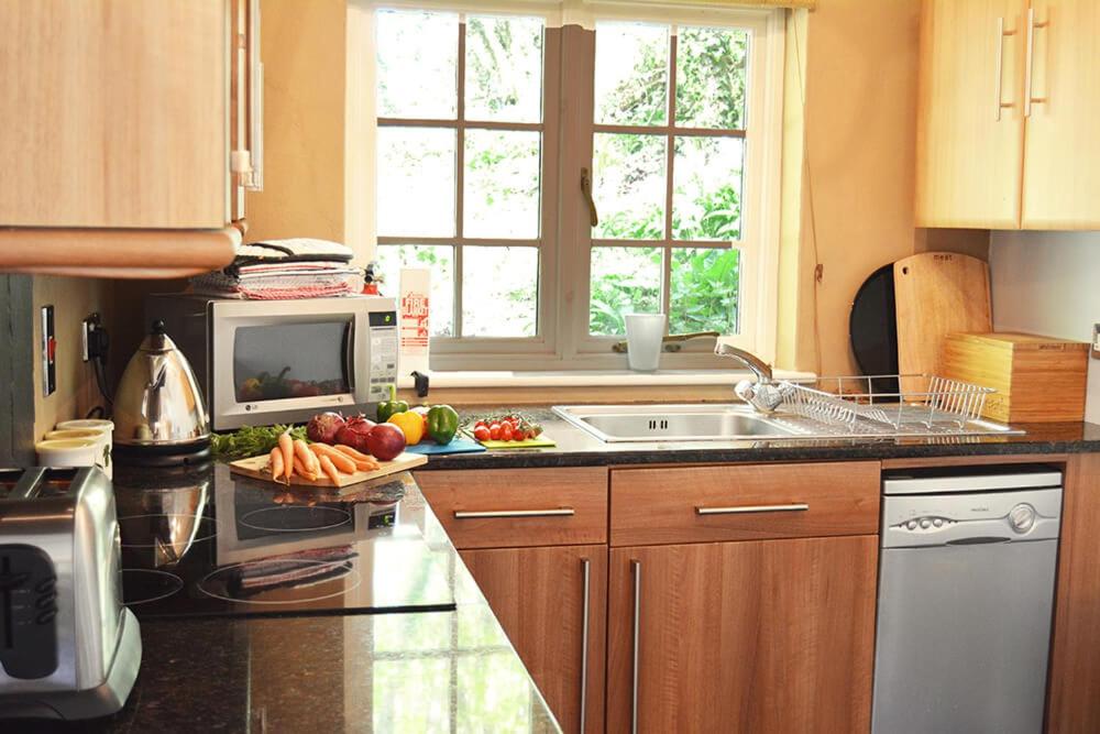 a kitchen with a sink and a counter with fruits and vegetables at Spring Water Barn in Helston