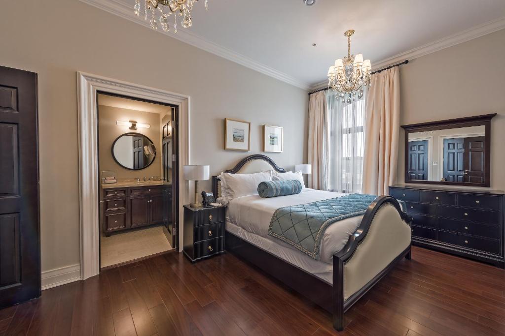 a bedroom with a bed and a mirror and a chandelier at Sydney Boutique Inn & Suites in Charlottetown