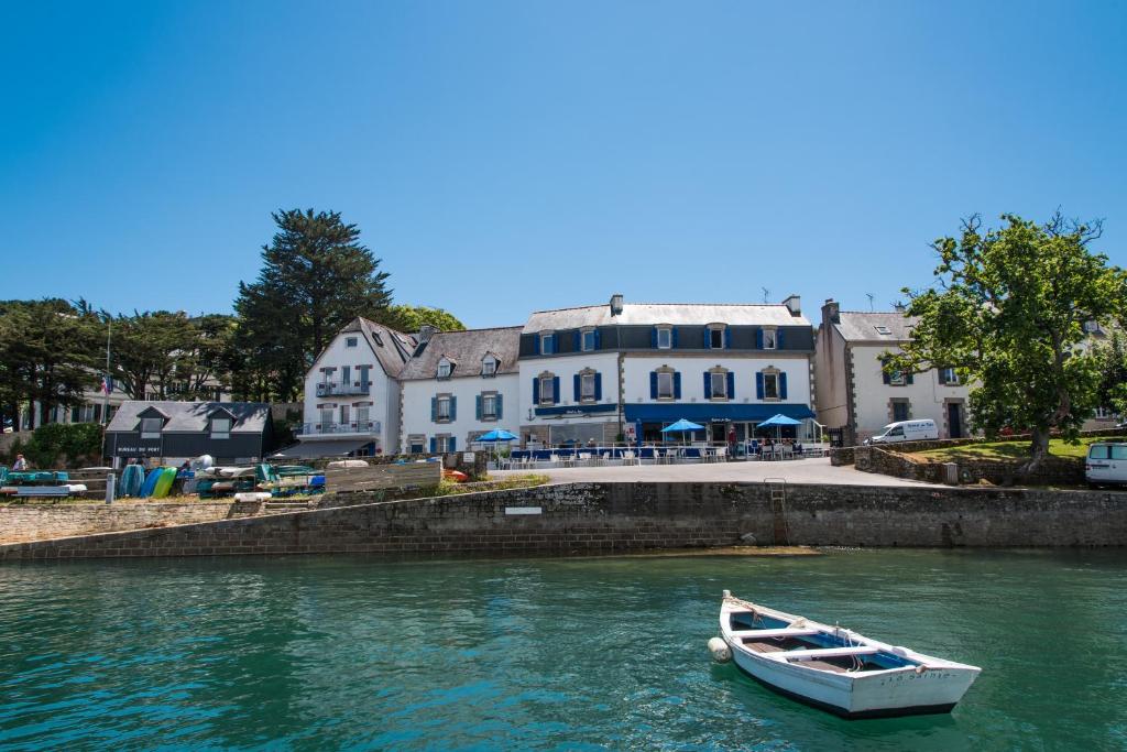 a boat in the water in front of a building at Hotel Du Bac in Combrit