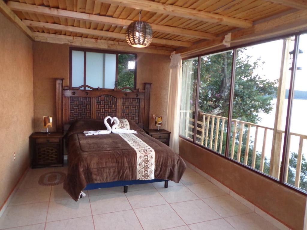 a bedroom with a bed and a balcony with windows at ZIRAHUÉN CUIN Habitaciones Rústicas in Zirahuén