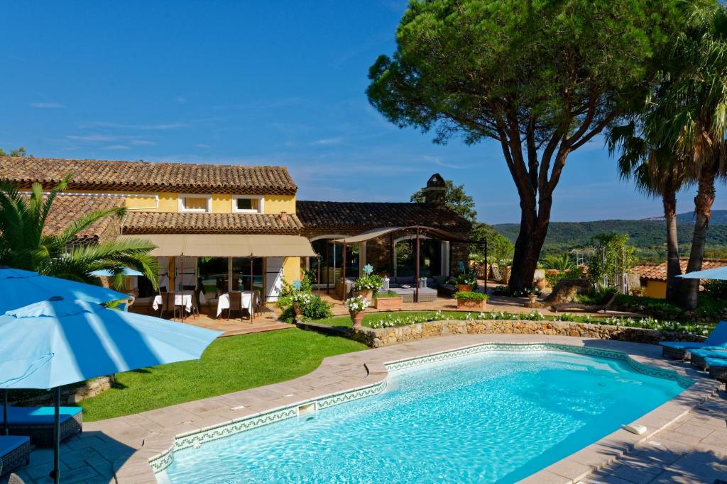 a swimming pool in front of a house with an umbrella at Parfum de Roses in Cogolin