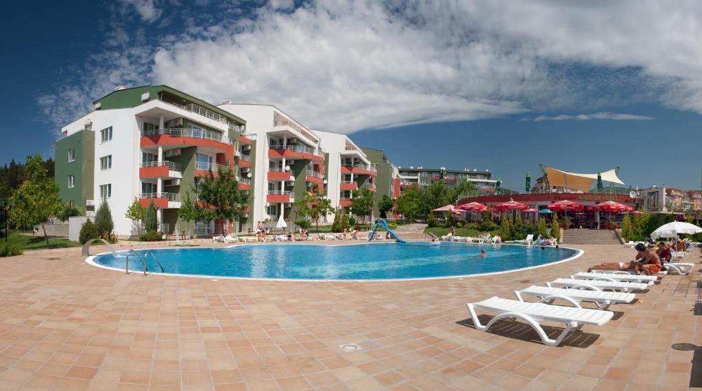 a resort with a swimming pool with chairs and umbrellas at Green Fort Private Apartments in Sunny Beach
