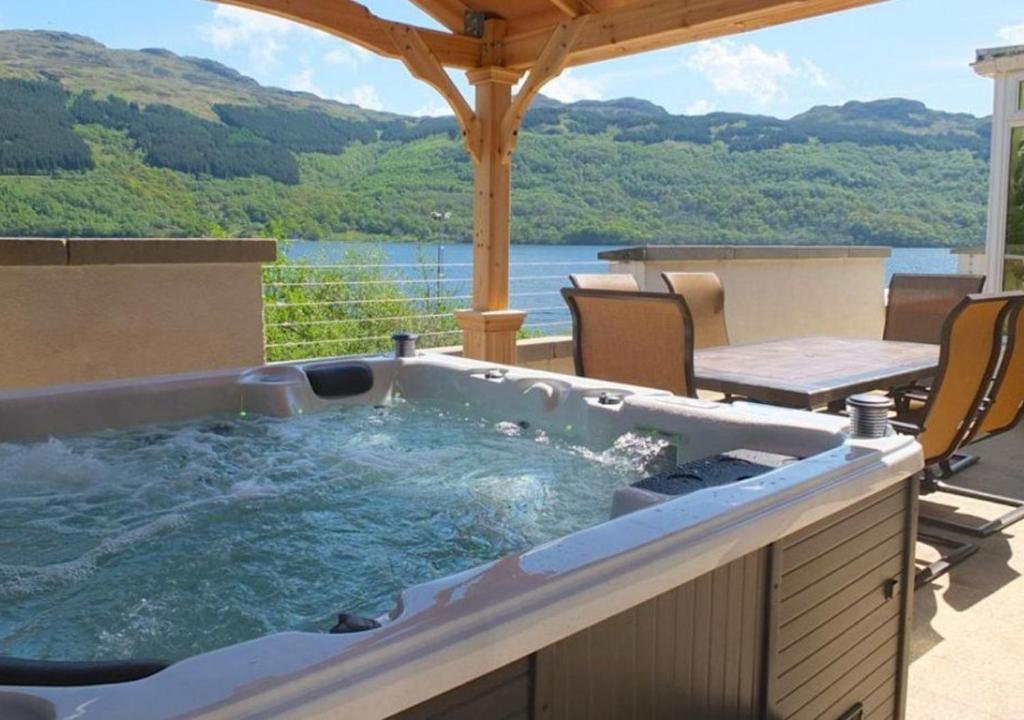 a hot tub on a patio with a table and chairs at Jenny's Bay at Loch Goil in Lochgoilhead