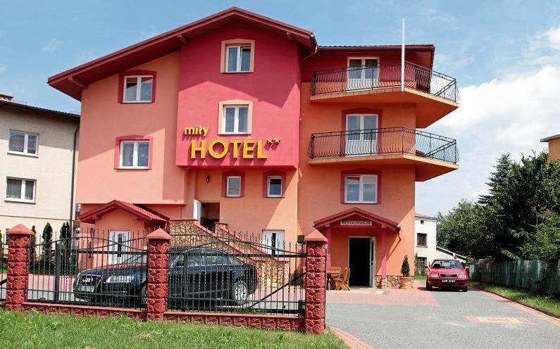 un grand bâtiment rose avec un panneau d'hôtel dans l'établissement Hotel Miły, à Krosno