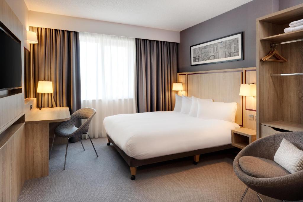 a hotel room with a bed and a desk and chairs at Leonardo Hotel London Watford in Watford