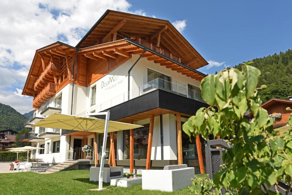 a house with a wooden roof at Dolomeet Boutique Hotel in Pinzolo
