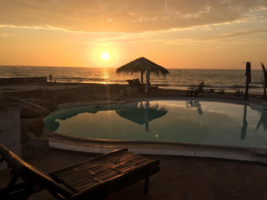 a swimming pool with a sunset in the ocean at Waltako Beach Culture in Canoas De Punta Sal