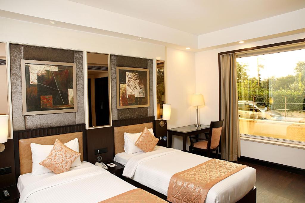Una habitación de hotel con dos camas y una ventana. en Inde Hotel Vista Woods Huda City Centre, Gurgaon, en Gurgaon