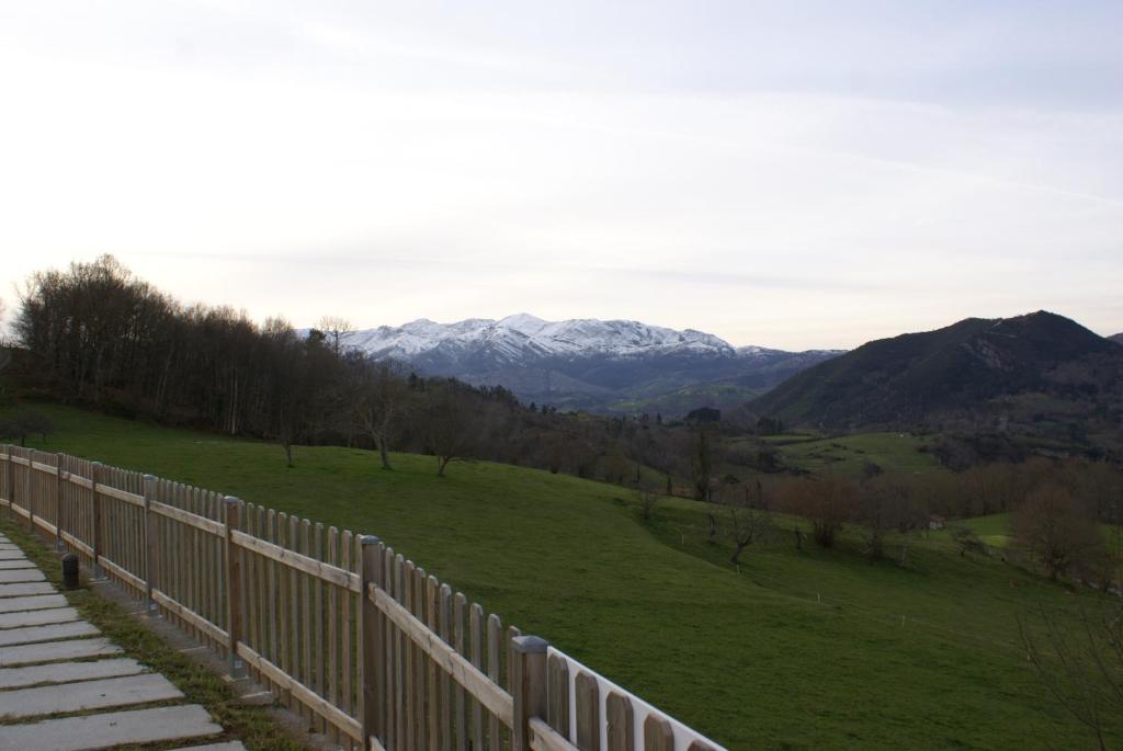 een hek op een heuvel met bergen op de achtergrond bij Apartamentos La Senda in San Juan de Parres