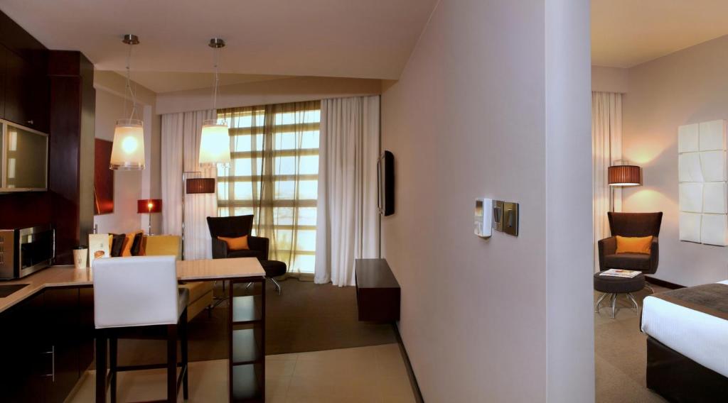 a living room and a kitchen with a table and chairs at Centro Sharjah in Sharjah