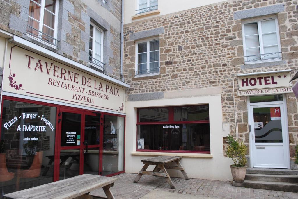 a row of shops with benches in front of a building at Taverne de la paix in La Ferté-Macé