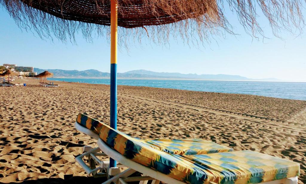 una silla de playa bajo una sombrilla en una playa en Carihuela Sun Beach, en Torremolinos