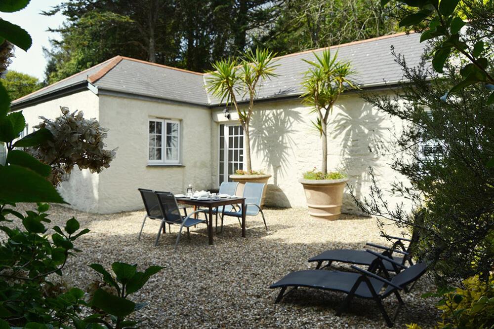 una casa y un patio con mesa y sillas en St Corantyn Cottage, en Helston