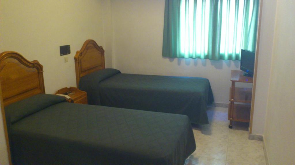 a small bedroom with two beds and a television at Hostal Juanito in Móstoles