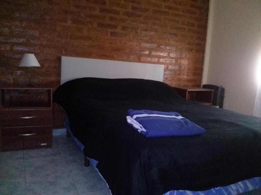 Un dormitorio con una cama con una camisa azul. en Departamentos Las Grutas Enjoy en Las Grutas