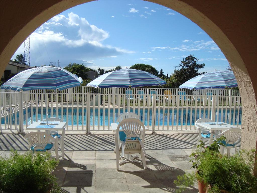 a patio with chairs and umbrellas next to a pool at Hotel de la Poste in Peymeinade
