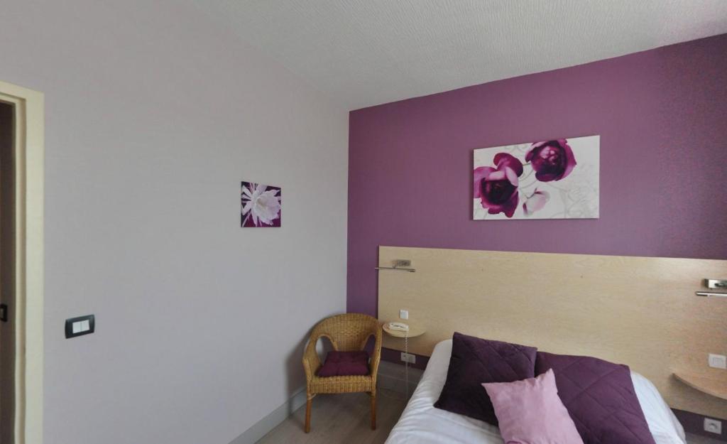 a bedroom with a bed with a purple wall at Logis Hôtel-Restaurant La Croix Couverte in Mayenne