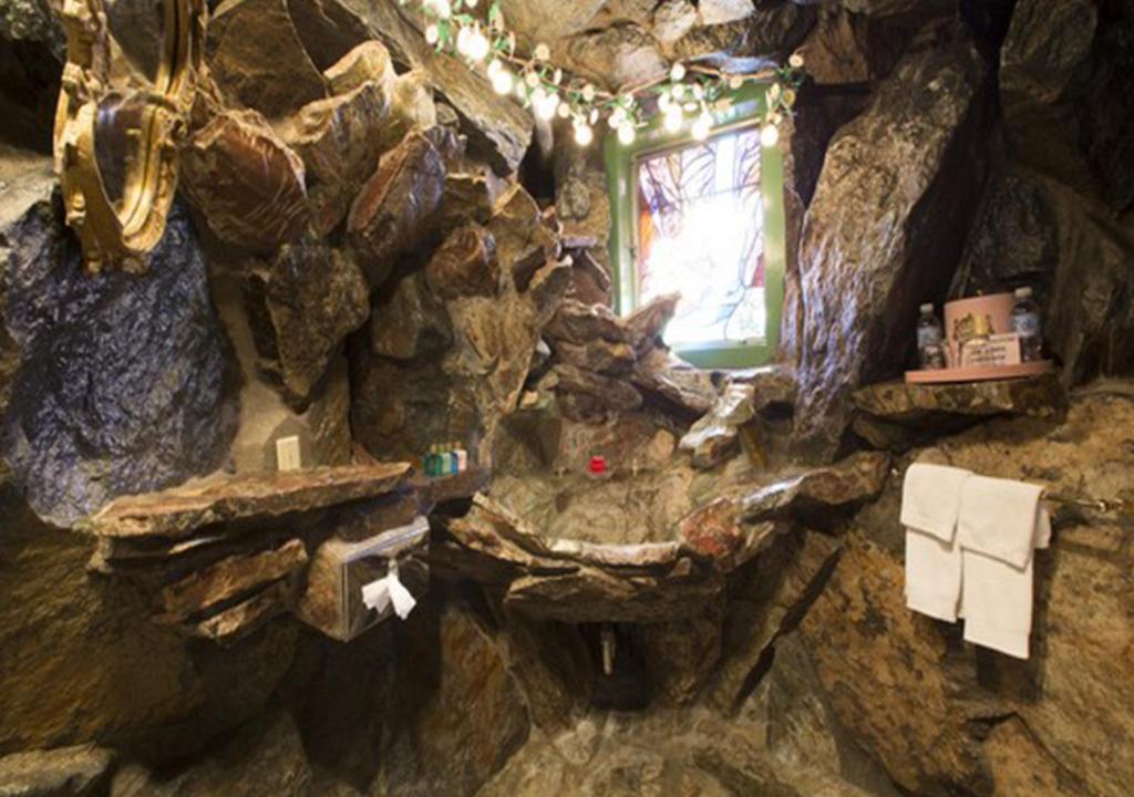 a stone bathroom with a rock wall with a window at Madonna Inn in San Luis Obispo