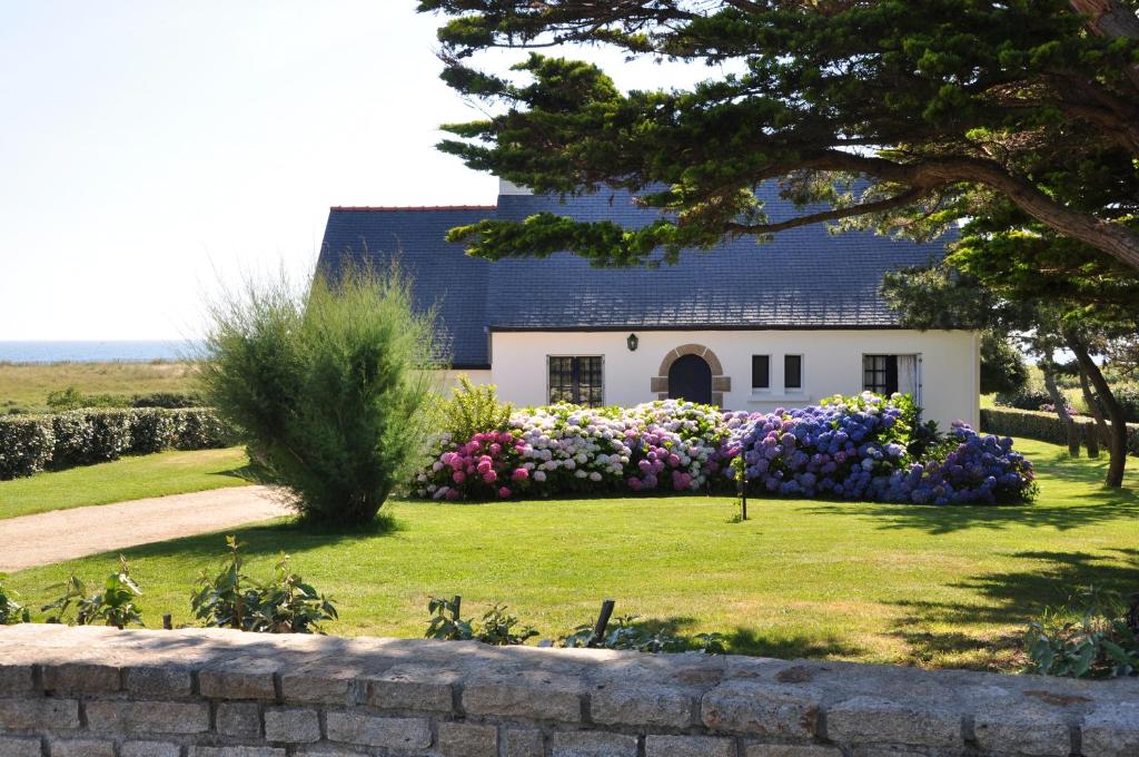 a house with flowers in front of a yard at Maison de vacances au bord de la plage in Trégunc