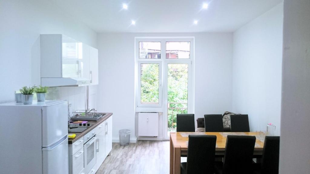 Una cocina con una mesa y un refrigerador blanco. en AVI City Apartments GoodHouse, en Düsseldorf