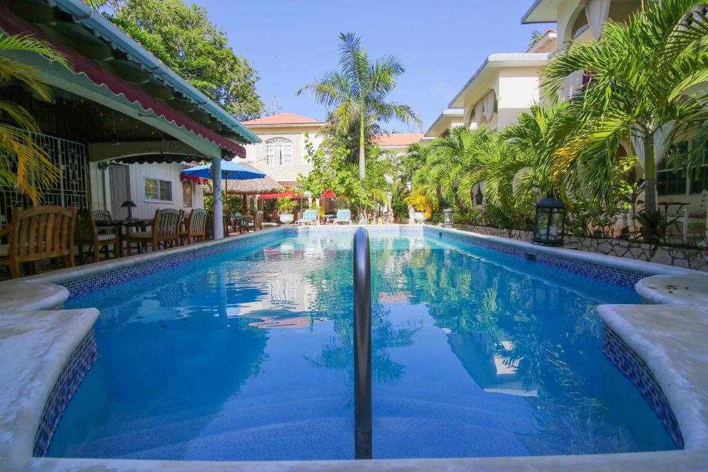 una piscina en un complejo con palmeras en Rayon Hotel en Negril