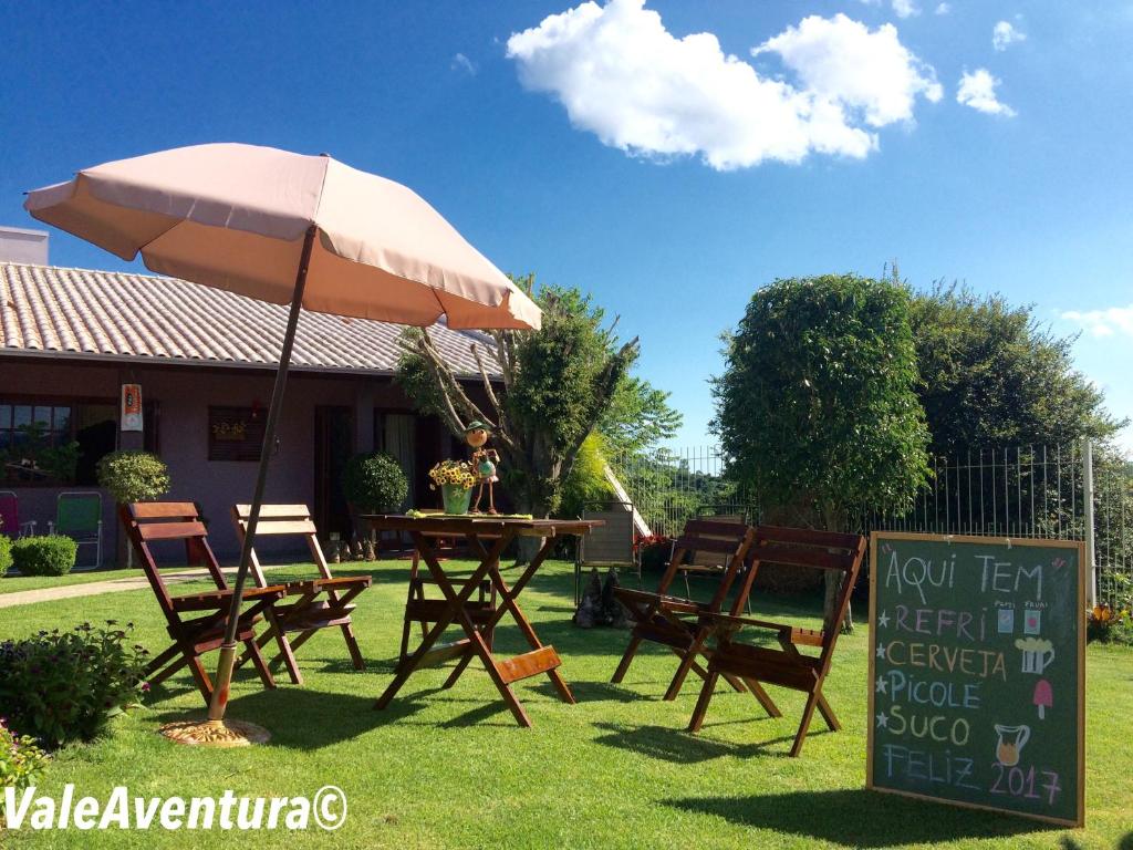 Vale Aventura في Colinas: طاولة وكراسي مع مظلة في العشب