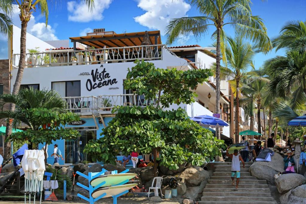 a hotel on the beach with palm trees and chairs at Hotel Vista Oceana Sayulita in Sayulita