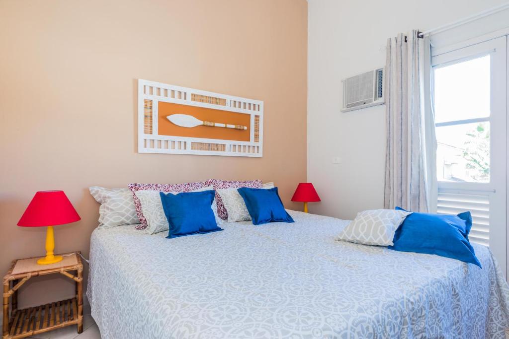 a bedroom with a bed with blue pillows and a window at Bhaus Juqueí | Beach House | Praia in Juquei