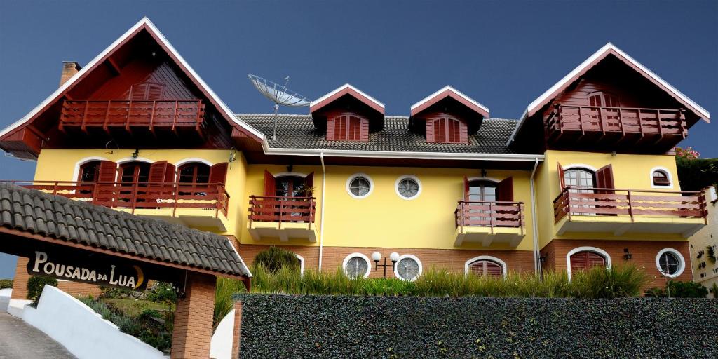 een geel en bruin huis met een zwart dak bij Pousada da Lua in Campos do Jordão