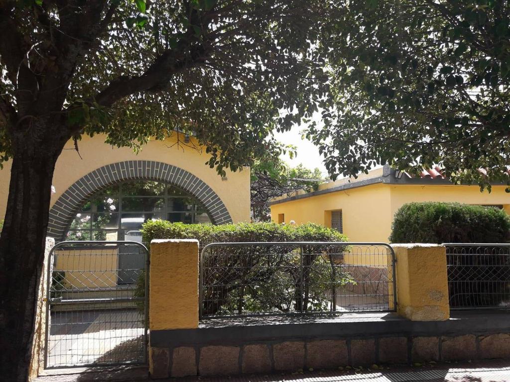 una cerca frente a un edificio con un árbol en Guest House Mielaloe en Capilla del Monte