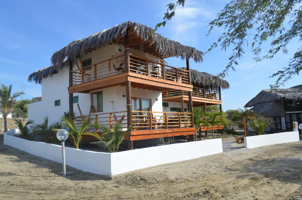 ein Haus am Strand mit einem Strohdach in der Unterkunft Casa BlueSky in Los Órganos
