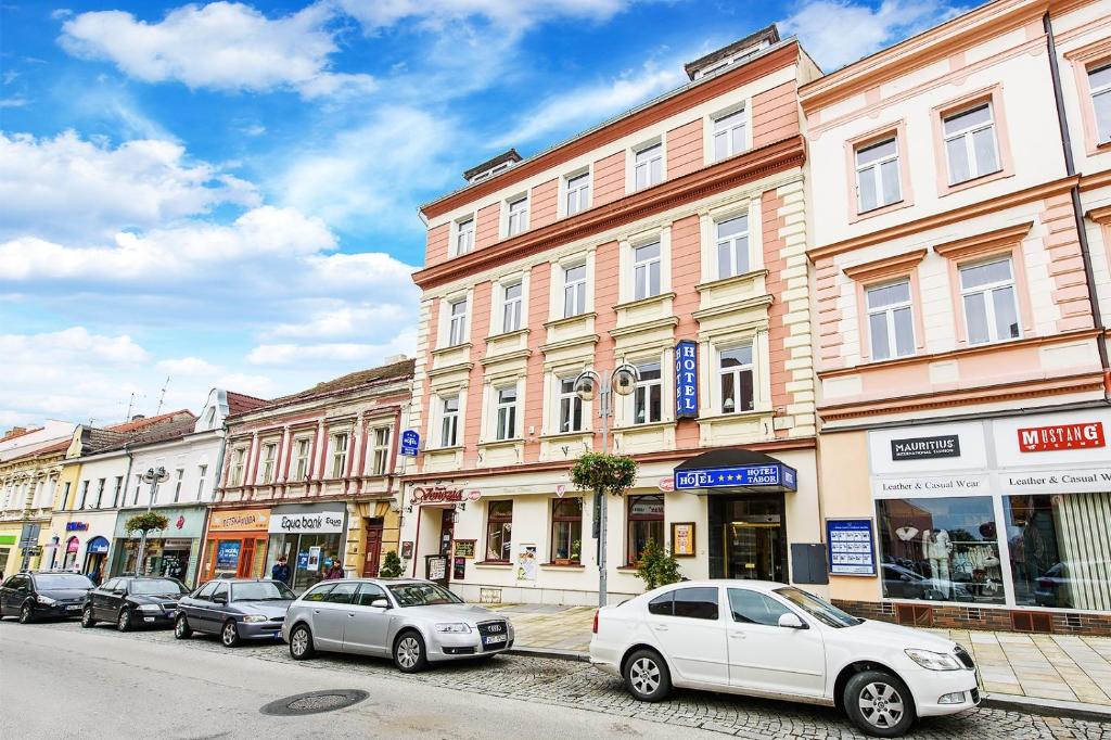 a group of cars parked in front of buildings at Hotel Tábor in Tábor
