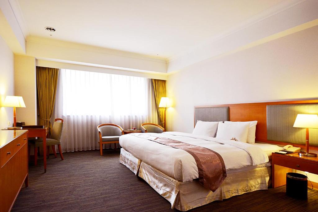 a hotel room with a large bed and a desk at Fushin Hotel Taichung in Taichung