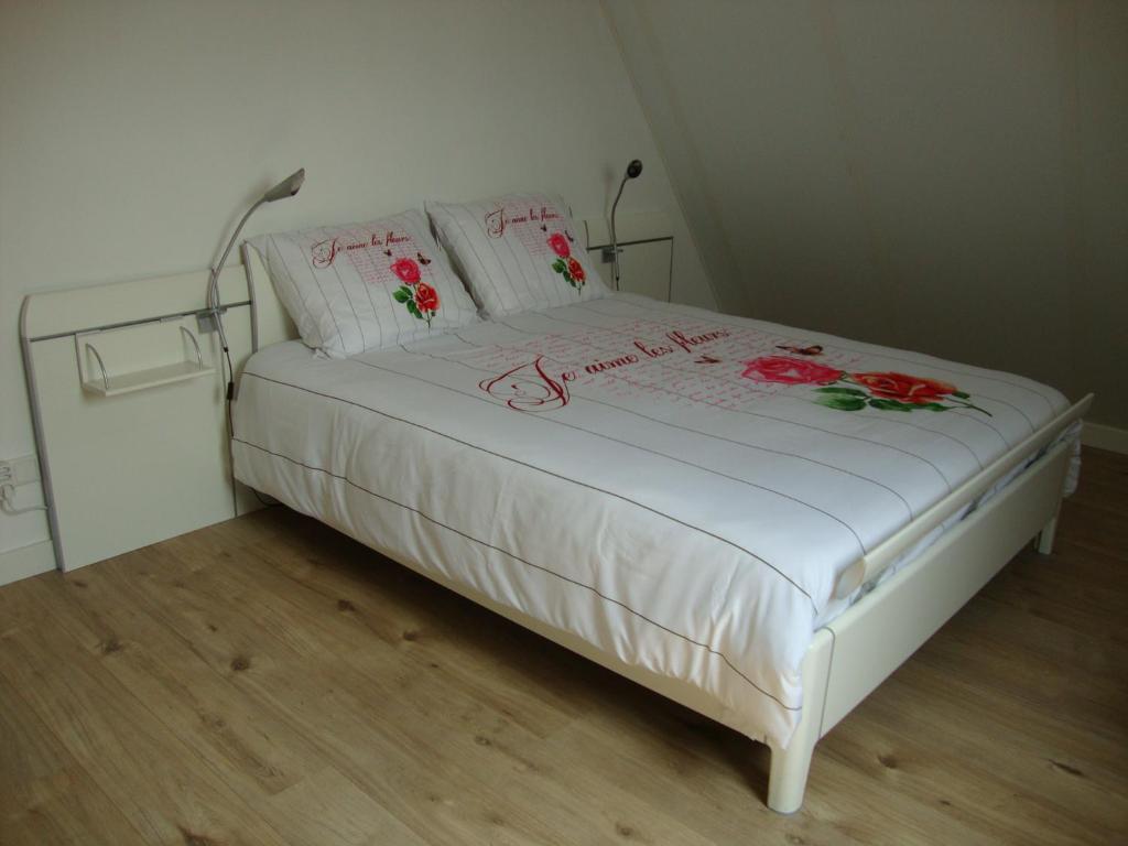 een wit bed met bloemen erop in een kamer bij B&B Hanenberg in Oijen