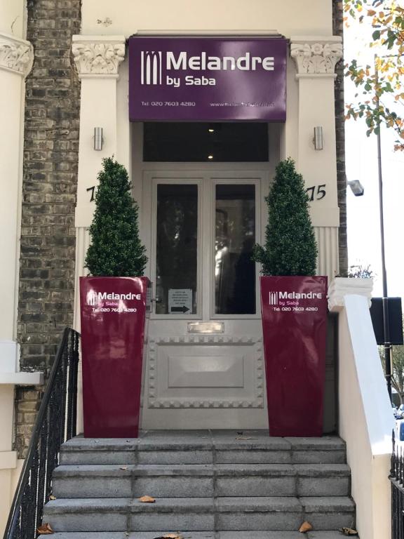 a front door of a building with two trees at Melandre Hotel By Saba in London